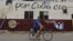 Un hombre cruza en bicicleta frente a un muro con mensajes alusivos a las elecciones generales en Cuba.