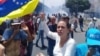 La opositora María Corina Machado sostiene una bandera venezolana al revés en protesta contra el gobierno de Maduro.