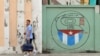 Una pareja camina junto a un cartel con el emblema de los Comités de Defensa de la Revolución (CDR), en La Habana, Cuba. 